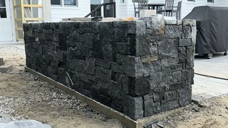 Outdoor stone retaining wall made of dark granite blocks